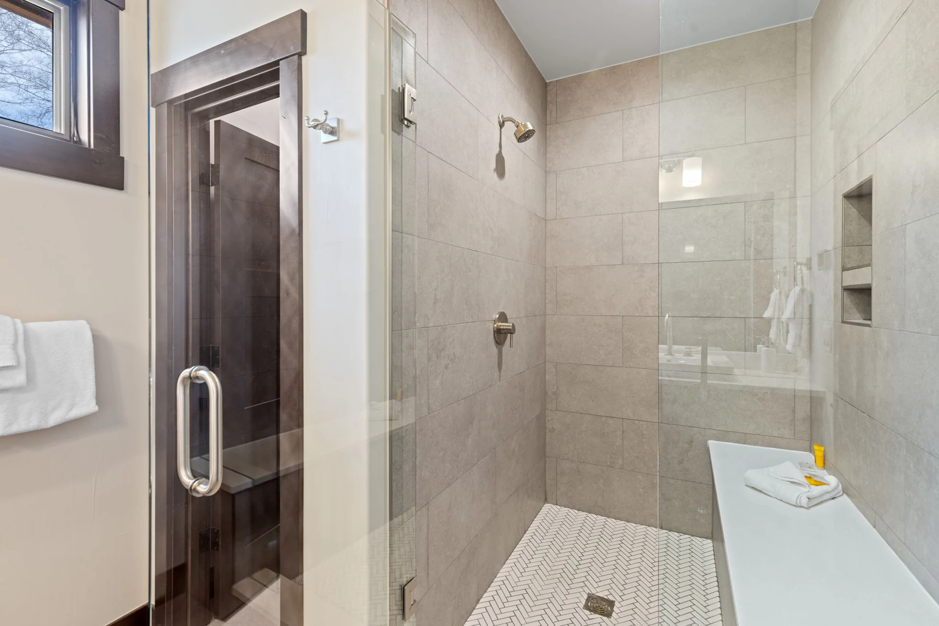 Vendette Peak, bathroom: Glass-enclosed shower with beige wall tile, a mosaic floor, metal fixtures, and a recessed niche, luxury vacation rental in Silverthorne, Colorado