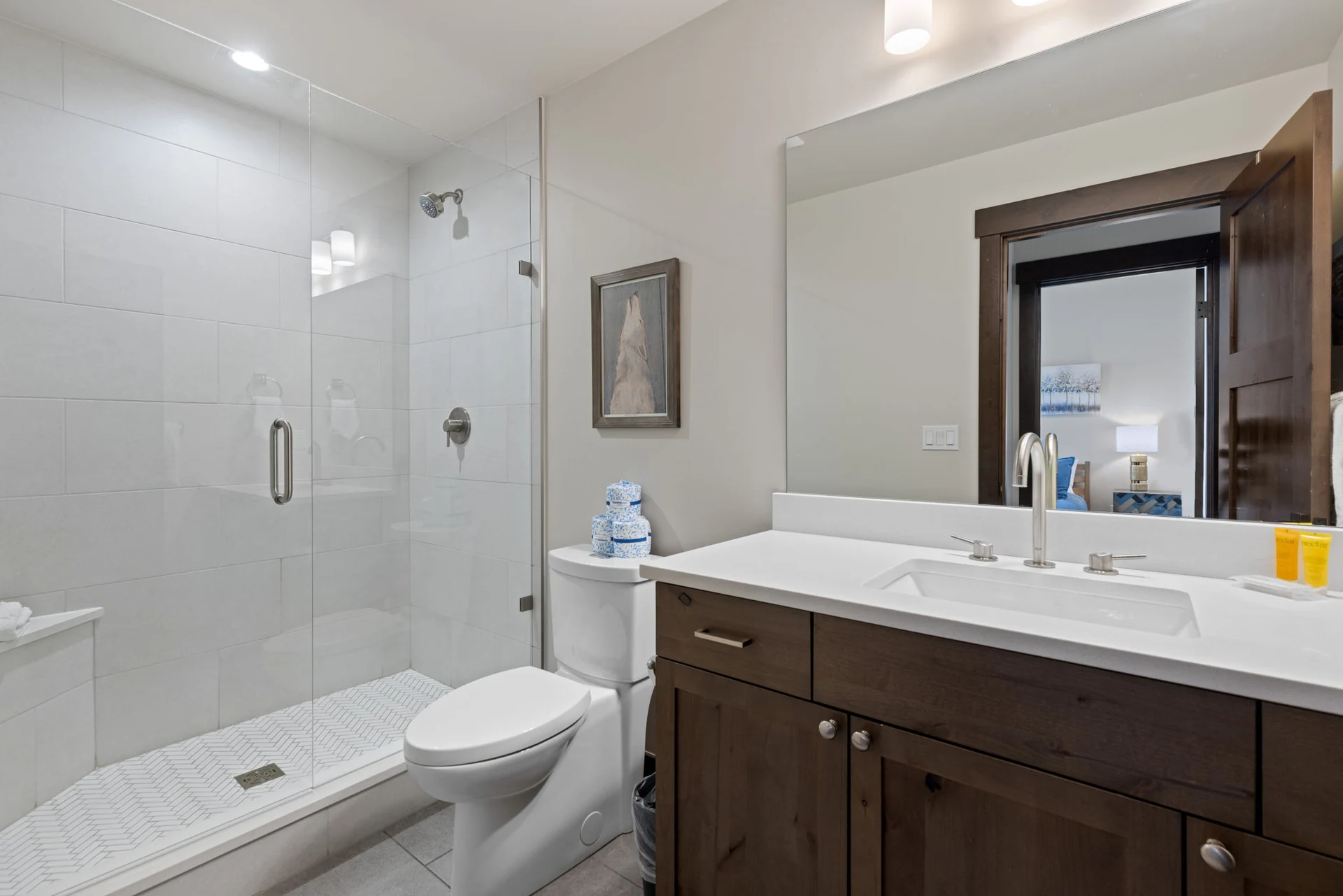 Vendette Peak, bathroom: Bathroom with a glass shower, patterned floor, toilet, and dark wood vanity with a white counter, luxury vacation rental in Silverthorne, Colorado