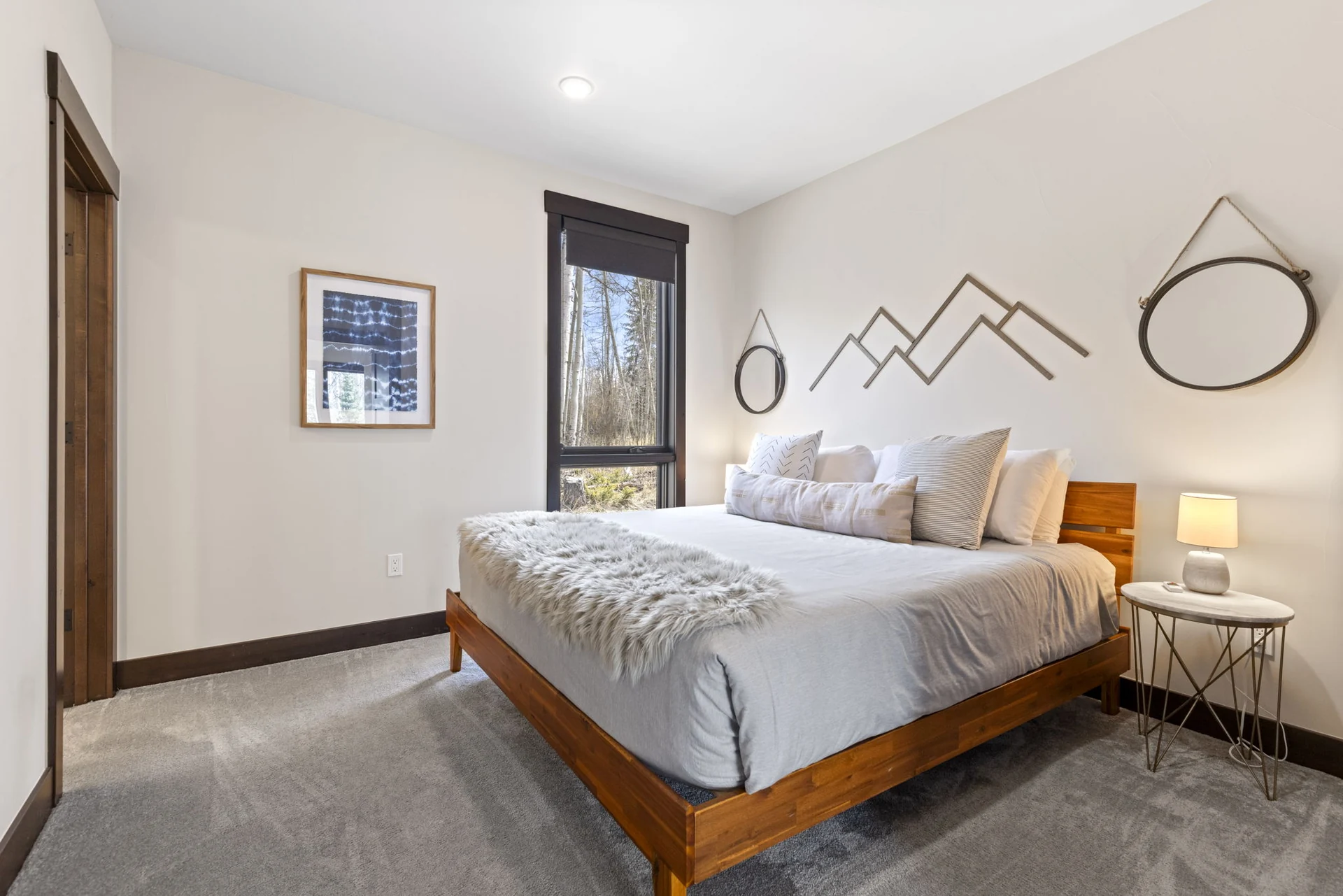 Vendette Peak, bedroom: Bedroom with white bedding, a gray throw, wood bed frame, mountain-line wall art, and a narrow window, luxury vacation rental in Silverthorne, Colorado
