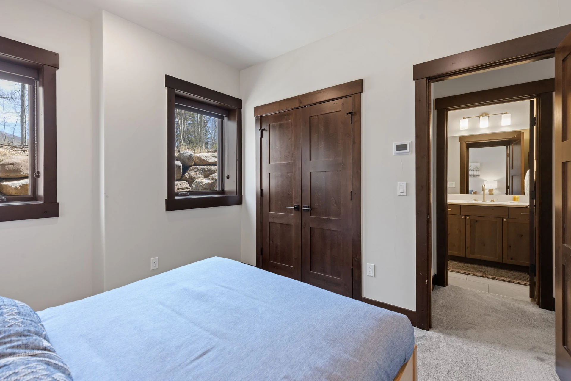 Vendette Peak, bedroom: Opposite angle of the blue-bedded room, showing wood closet doors, windows, and an open vanity doorway, luxury vacation rental in Silverthorne, Colorado