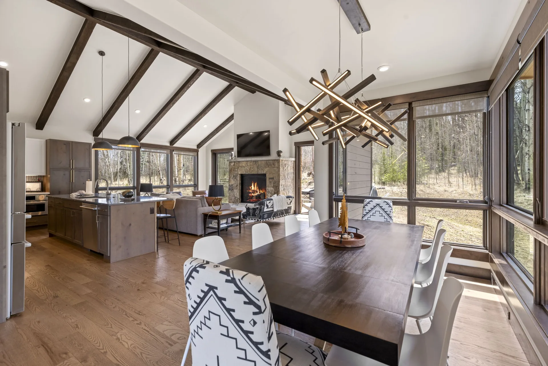 Vendette Peak, dining room: Dining area looking toward the kitchen island, with a branching pendant and floor-to-ceiling windows, luxury vacation rental in Silverthorne, Colorado