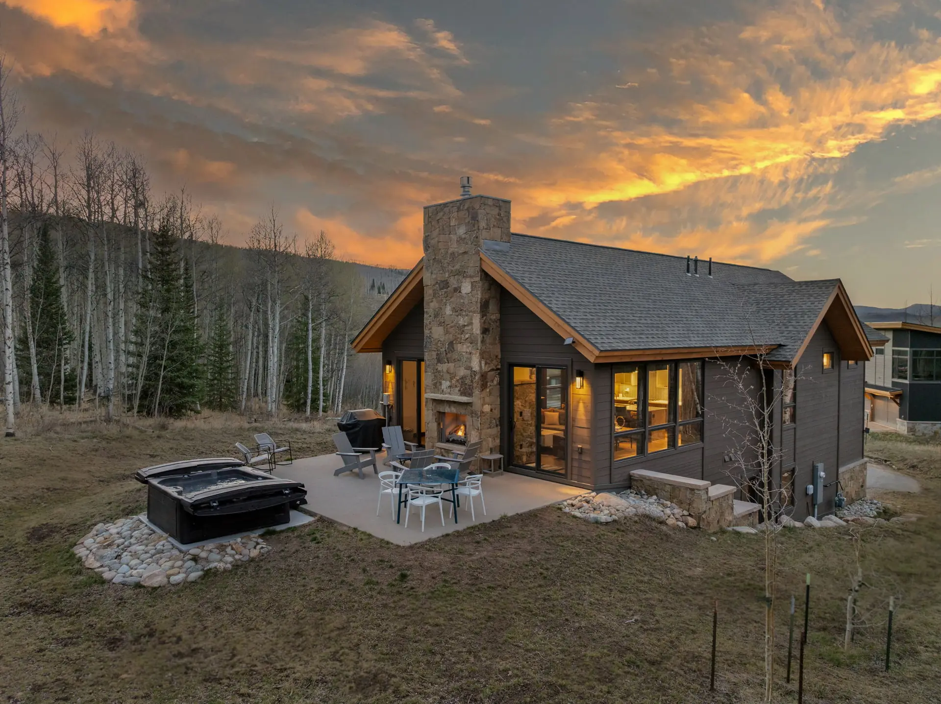 Vendette Peak, exterior: Side view of the home at dusk, with the hot tub and outdoor seating beside the aspen grove, luxury vacation rental in Silverthorne, Colorado