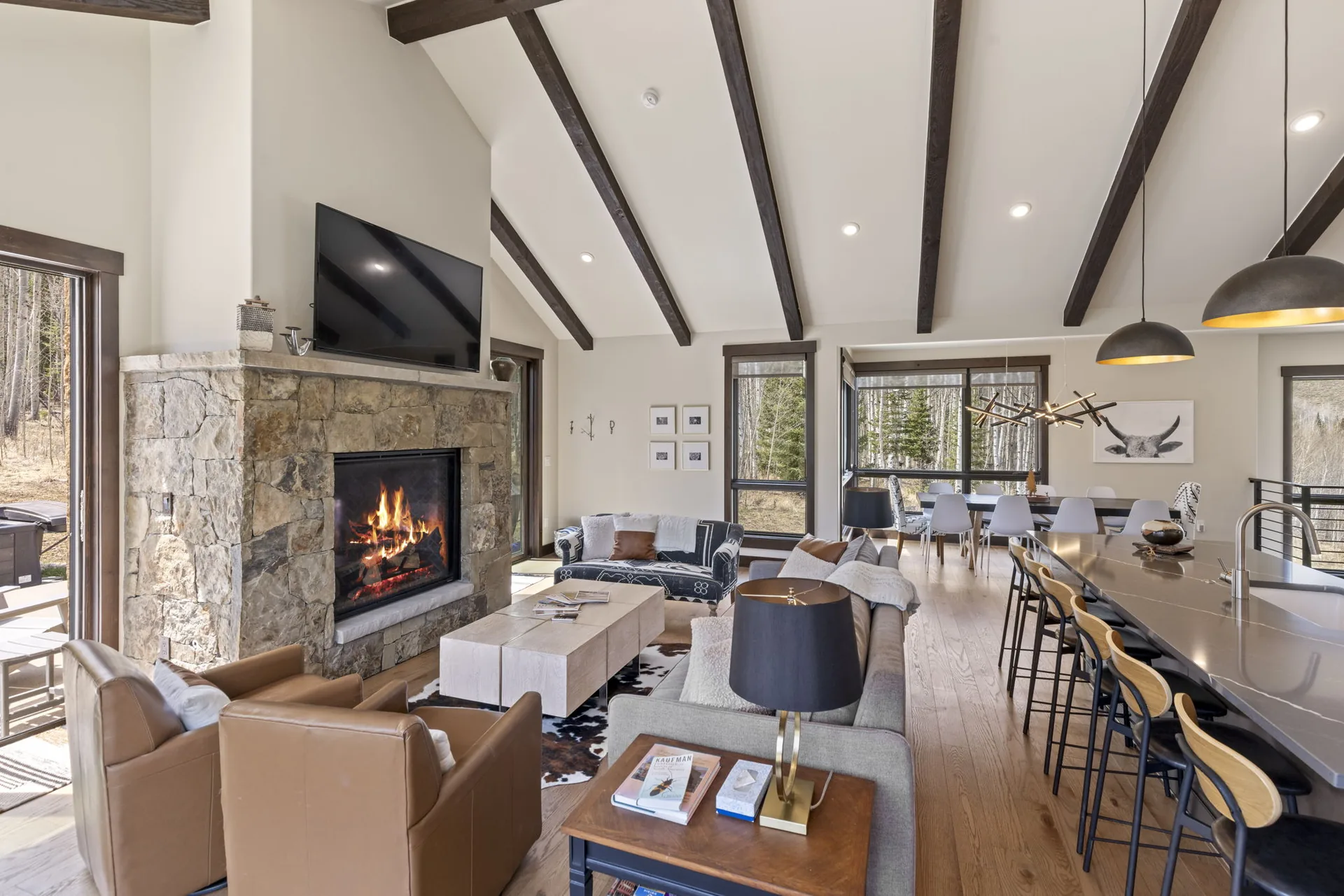Vendette Peak, living room: Reverse view of the great room, with the fireplace, seating area, kitchen stools, and forest-facing windows, luxury vacation rental in Silverthorne, Colorado