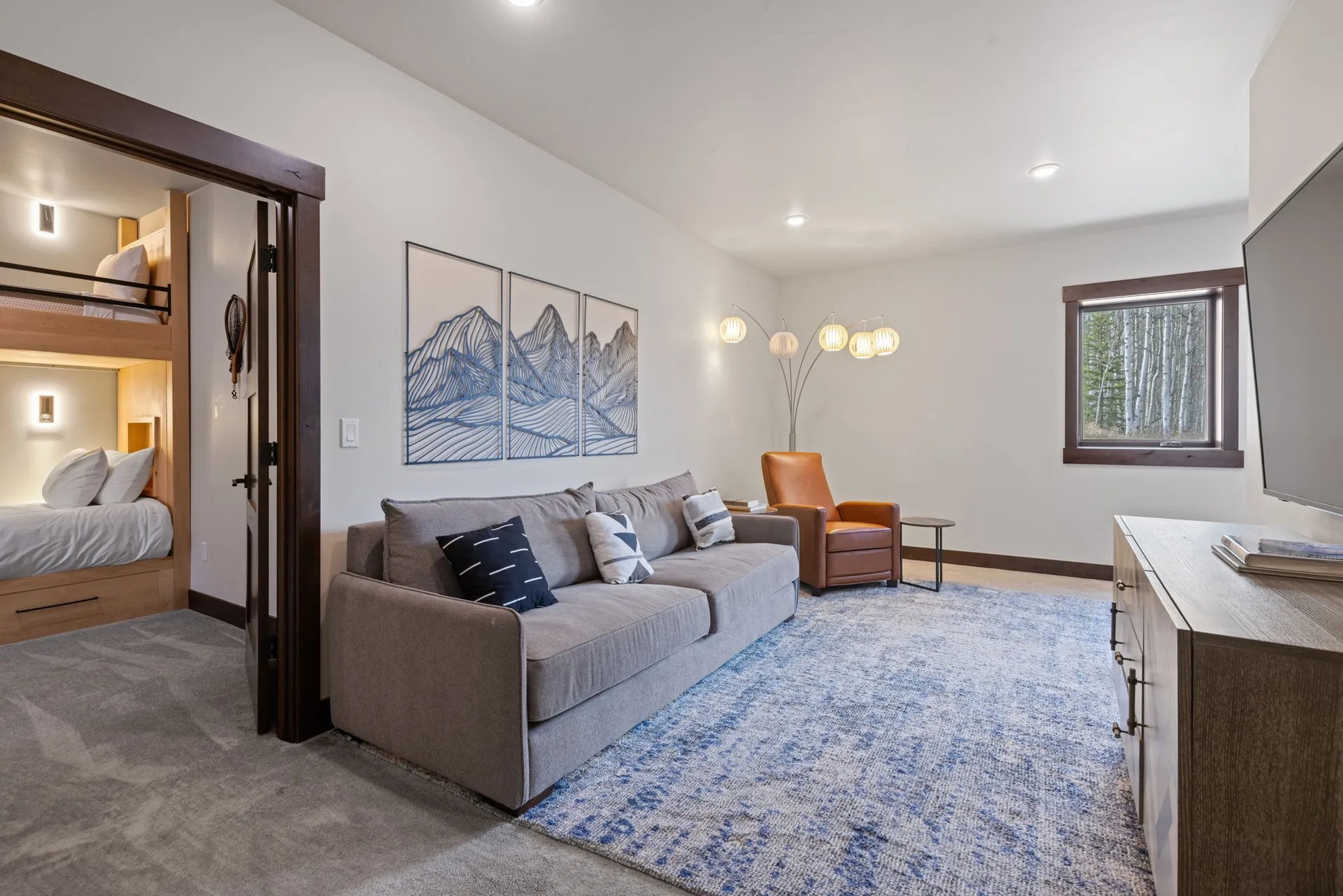 Vendette Peak, living room: Side view of the second sitting area, with a gray sofa, mountain prints, orange chair, and small window, luxury vacation rental in Silverthorne, Colorado